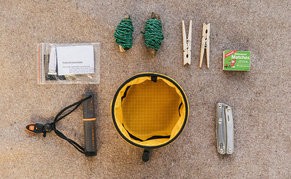 A Small Travel Tray with a possible loadout (including a few bolts of bungee cord, a couple clothespins, a box of matches, a knife, a portable flashlight, and a bag patch kit).